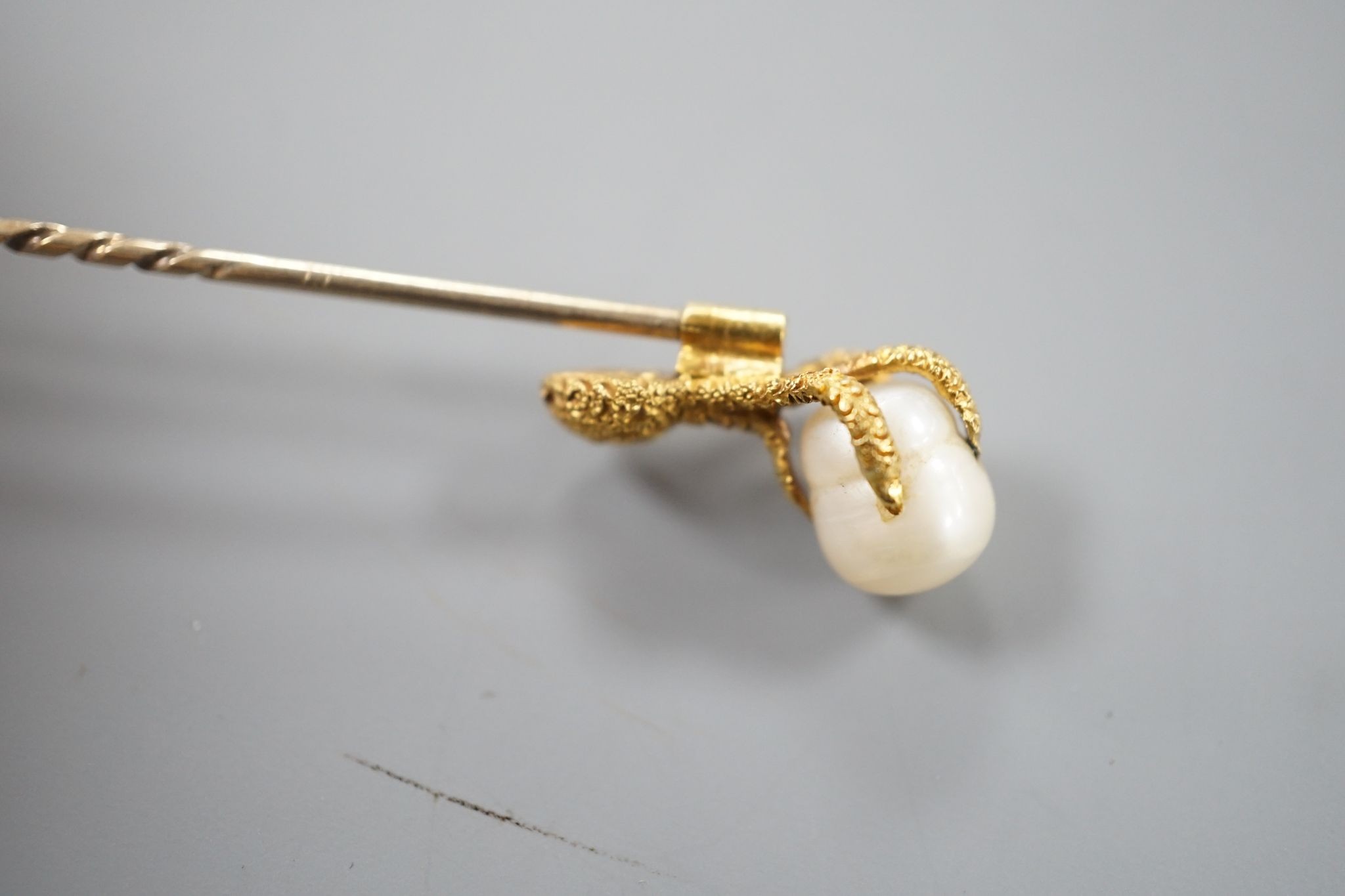 A 19th century yellow metal stick pin, the terminal modelled as an eagle's claw grasping a baroque pearl, 78mm, gross weight 3.3 grams, with box.